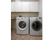 Bright laundry room featuring a modern, front-load washer and dryer with white cabinets and neutral tile floor at 321 Barbara Cir, Belleair, FL 33756