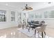 Bright living room featuring large windows, tile floors, a ceiling fan, and comfortable seating with modern decor at 321 Barbara Cir, Belleair, FL 33756