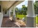 Inviting covered porch area with brick flooring and decorative chairs overlooking a well manicured, fenced backyard at 321 Barbara Cir, Belleair, FL 33756