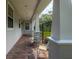 Covered porch featuring brick flooring and two seating chairs with decorative cushions for relaxing outdoors at 321 Barbara Cir, Belleair, FL 33756