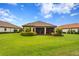 A beautifully landscaped backyard with a screened-in lanai, lush green grass, and manicured shrubs under a bright blue sky at 3214 Forsythia Dr, Odessa, FL 33556
