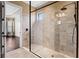 Modern bathroom featuring a glass shower with rain shower head and tile surround, with a view into another room at 3214 Forsythia Dr, Odessa, FL 33556