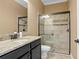 Bathroom featuring granite counters, a black vanity, and a glass-enclosed shower with neutral tile surround at 3214 Forsythia Dr, Odessa, FL 33556
