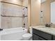 Bathroom featuring a bathtub with shower head, tiled walls, dark vanity with light countertop, and a toilet at 3214 Forsythia Dr, Odessa, FL 33556