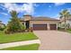 Charming home with a tile roof, a three-car garage, a brick paver driveway, and professionally landscaped front yard at 3214 Forsythia Dr, Odessa, FL 33556