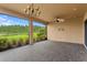 Spacious covered patio area with brick flooring, ceiling fan, and scenic views of the lush backyard at 3214 Forsythia Dr, Odessa, FL 33556