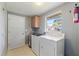 Functional laundry room with a washer, dryer, storage cabinet, and a window for natural light at 4307 Foxglen Ln, Tampa, FL 33624