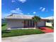 Charming single-story home featuring a well-manicured lawn, red driveway, and a decorative palm tree at 5390 Magnolia N Trl, Pinellas Park, FL 33782