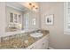 Charming powder room with granite countertop, white cabinetry and decorative mirror at 610 S Rome Ave # 602, Tampa, FL 33606