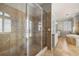 Large walk-in shower featuring frameless glass door and travertine tile in Primary bathroom at 610 S Rome Ave # 602, Tampa, FL 33606