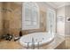 Beautiful bathroom featuring large tub, shuttered window and travertine tile at 610 S Rome Ave # 602, Tampa, FL 33606
