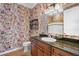 Bathroom showcasing unique wallpaper, wood cabinets, and granite countertops at 610 S Rome Ave # 602, Tampa, FL 33606