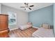Bright bedroom featuring two twin beds, wood floors, and a ceiling fan, complemented by natural light from a window at 7809 E 114Th Ave, Temple Terrace, FL 33617