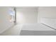 Minimalist bedroom with white bedding and window featuring a view of the neighborhood at 8612 Ivy Stark Blvd, Wesley Chapel, FL 33545