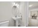 Well-lit powder room with pedestal sink, oval mirror, and tile flooring at 8612 Ivy Stark Blvd, Wesley Chapel, FL 33545
