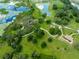 An aerial shot of a green park, a pond, playground and parking with the sky reflected in the water at 8749 Drummer Plank Dr, Wesley Chapel, FL 33545