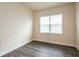 Cozy bedroom with neutral walls, dark flooring, and natural light from the window at 8749 Drummer Plank Dr, Wesley Chapel, FL 33545