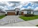 Inviting home featuring a two-car garage, brick accents, and manicured landscaping at 8749 Drummer Plank Dr, Wesley Chapel, FL 33545