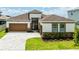 Inviting home featuring a two-car garage, brick accents, and manicured landscaping at 8749 Drummer Plank Dr, Wesley Chapel, FL 33545