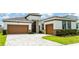 Inviting home featuring a two-car garage, brick accents, and manicured landscaping at 8749 Drummer Plank Dr, Wesley Chapel, FL 33545
