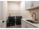 A functional laundry room is equipped with modern washer and dryer units, a utility sink, and ample storage at 8749 Drummer Plank Dr, Wesley Chapel, FL 33545