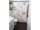 Bathroom featuring a floral shower curtain, dark plank flooring, and wall-mounted shelving at 1006 Harvest Moon Dr, Seffner, FL 33584