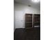 A bedroom with dark wood-look floors, bookshelves, and a white door at 1006 Harvest Moon Dr, Seffner, FL 33584