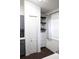 View of a walk-in pantry adjacent to the kitchen featuring white cabinets, dark shelving, and patterned curtains at 1006 Harvest Moon Dr, Seffner, FL 33584