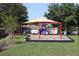 Community playground featuring swings, slide, and covered play area, surrounded by grass and mature trees at 1006 Harvest Moon Dr, Seffner, FL 33584