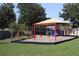 Community playground featuring swings, slide, and covered play area, surrounded by grass and mature trees at 1006 Harvest Moon Dr, Seffner, FL 33584