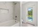 Bathroom featuring bathtub, tile accent wall, and a window offering poolside views at 10237 Deerwood Ave, Englewood, FL 34224