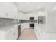 Modern kitchen featuring white cabinets, stainless steel appliances, and a stylish gray backsplash at 10237 Deerwood Ave, Englewood, FL 34224