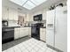 Efficient kitchen with white cabinets, black appliances, and checkered backsplash at 10636 Millriver Dr, New Port Richey, FL 34654