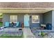 Inviting front porch with comfortable seating, a charming blue door, and manicured landscaping, creating a warm entrance at 12316 Eldon Dr, Largo, FL 33774