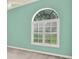 A sunlit bedroom with a large, arched window fitted with plantation shutters offering privacy at 13321 Lewis Raulerson Rd, Dover, FL 33527