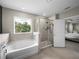 A luxurious tub sits beneath a large window, with a glass enclosed shower nearby at 13735 Wineberry Dr, Dade City, FL 33525