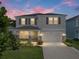 Charming two-story home featuring a well-manicured lawn, stone accents, gray exterior, and an attached two-car garage at 13735 Wineberry Dr, Dade City, FL 33525