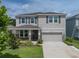 Well-maintained two-story home boasting stone accents, an attached garage, and a lush front yard with mature landscaping at 13735 Wineberry Dr, Dade City, FL 33525