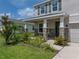 Inviting front porch with stone-accented columns and lush landscaping, offering a warm welcome to this lovely home at 13735 Wineberry Dr, Dade City, FL 33525