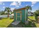 A green backyard shed with a wooden door provides additional storage space at 1529 Essex N Dr, St Petersburg, FL 33710