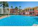 A large, clear, bright blue swimming pool at a resort-style community, surrounded by colorful buildings and palm trees at 16600 Gulf Blvd # 437, North Redington Beach, FL 33708