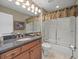 Well-lit bathroom featuring granite counters, a large mirror, and a shower-tub combo with sliding glass doors at 18917 Avenue Biarritz, Lutz, FL 33558