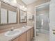 Bright bathroom featuring dual sinks, a vanity, and a glass-enclosed shower at 18917 Avenue Biarritz, Lutz, FL 33558
