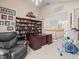 Spacious home office with bookshelves, a comfortable chair, and a view of the staircase at 18917 Avenue Biarritz, Lutz, FL 33558