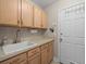 Functional laundry room has light wood cabinets, light countertops, sink, and access to the backyard at 18917 Avenue Biarritz, Lutz, FL 33558
