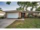 Charming single-story home featuring an attached garage, well-maintained lawn, and beautiful landscaping at 2010 Groveland Rd, Palm Harbor, FL 34683
