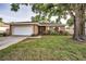 Charming single-story home with a large tree, well-kept lawn, and attached garage at 2010 Groveland Rd, Palm Harbor, FL 34683