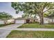 Inviting single-story home with a large tree, a well-kept lawn, and an attached garage at 2010 Groveland Rd, Palm Harbor, FL 34683