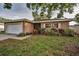 Charming single-story home featuring an attached garage, well-maintained lawn, and colorful landscaping at 2010 Groveland Rd, Palm Harbor, FL 34683