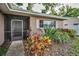 Welcoming front porch with colorful plants, a storm door, and a brick exterior accent at 2010 Groveland Rd, Palm Harbor, FL 34683